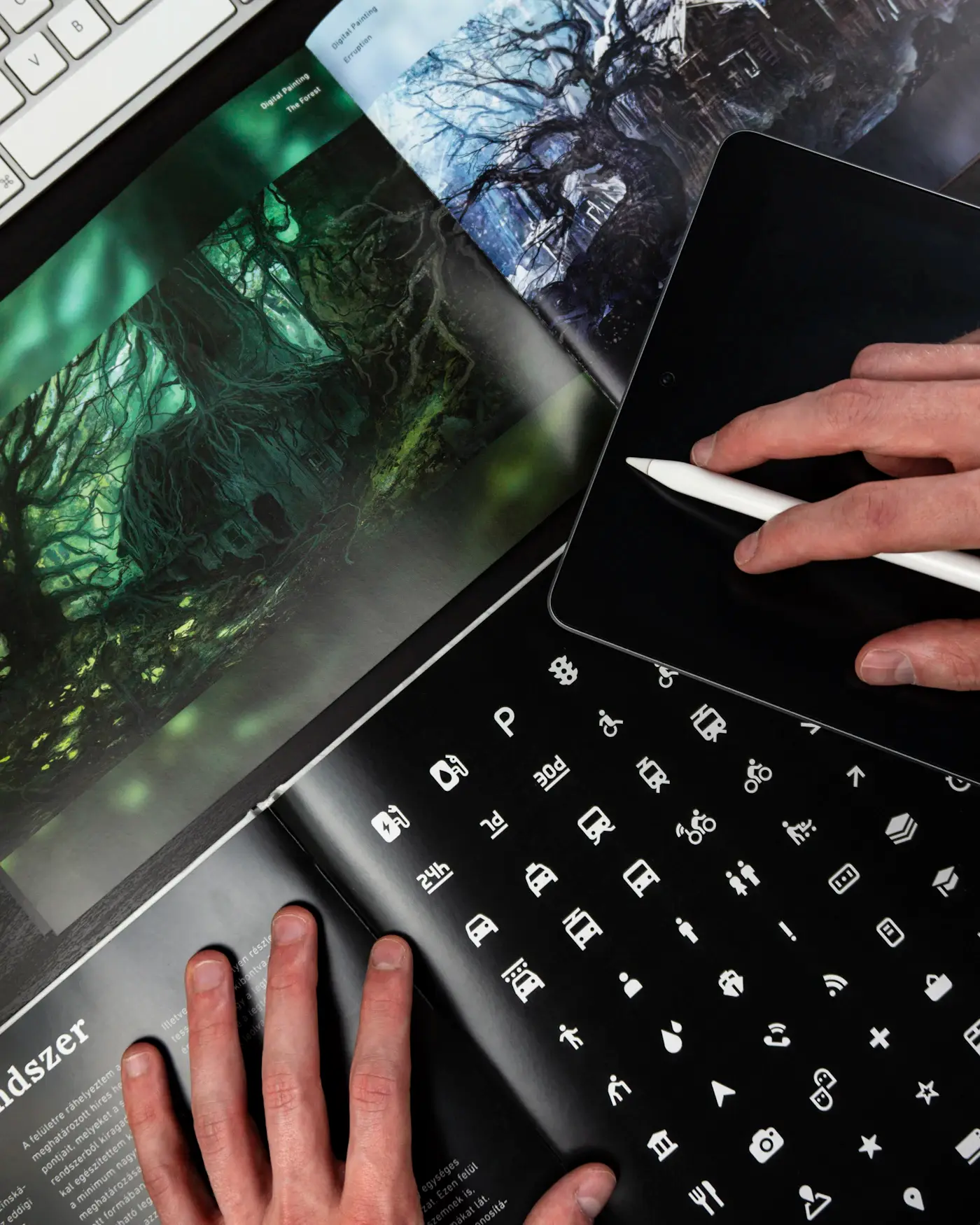 A designer working on a tablet beside a printed book of icon systems