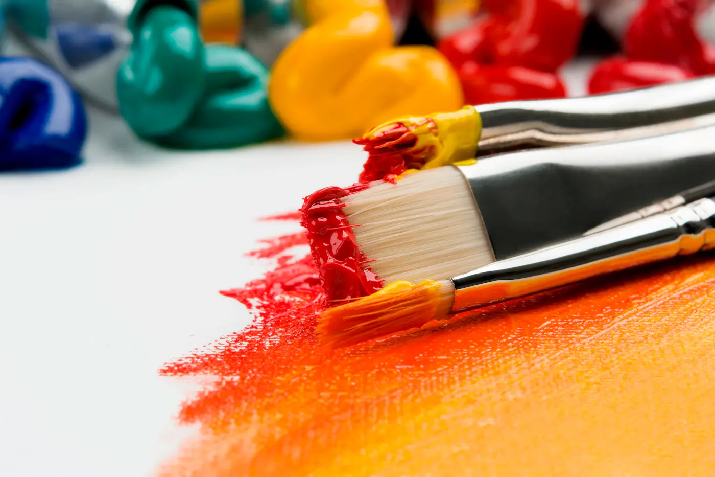 Paintbrushes resting on a surface streaked with mixed colour